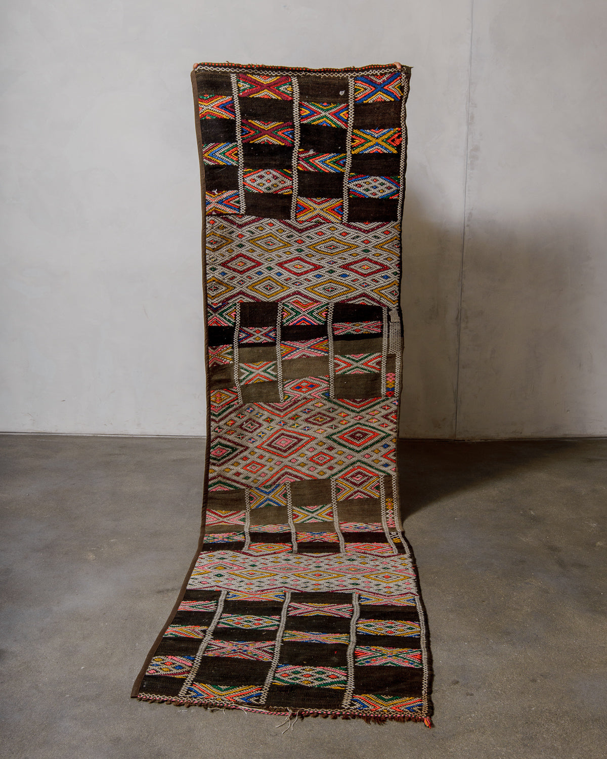 Colourful patterned kelim rug on a plain background.